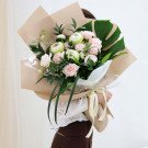 Bouquet of pale pink roses and cream roses with green leaves and lotus flowers.