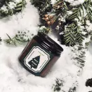 A Christmas scented candle with a pine, wood, and spice scent.