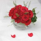 Red roses and carnations in a glass vase.