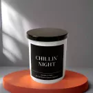 White candle with black label saying "CHILLIN' NIGHT" on an orange circular stand.