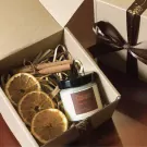 Candle gift set with dried oranges and cinnamon sticks in a cardboard box.