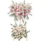 Two-tiered floral arrangement with pink and white roses, daisies, and greenery.