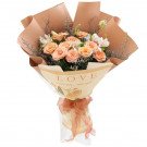 Bouquet of peach roses with alstroemeria and foliage, wrapped in brown paper and ribbon with "LOVE" text.