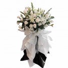 White lilies and roses in a funeral arrangement with white and black fabric.