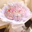 Rainbow gradient roses in a white bouquet with a silver crown.