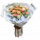 Bouquet of peach and cream roses wrapped in newspaper and tied with a brown ribbon.
