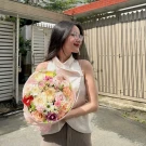 Pink and white roses, carnations, and filler flowers in a pink bouquet.