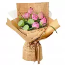 Pink lotus flower bouquet with lotus seed pods, wrapped in brown paper with "Romance Flowers" print.