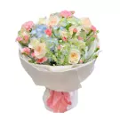 Bouquet of cream roses, pink carnations, and blue hydrangeas wrapped in white paper and tied with a pink ribbon.
