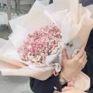 Pink baby's breath bouquet with sheer wrapping and a phone with a pearl accessory.