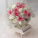 Bouquet of pink and white roses with baby's breath on a miniature piano.