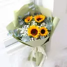 Bouquet of sunflowers, baby's breath, and eucalyptus in green paper.