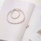 Pearl necklace on an open book with two loose pearls nearby.