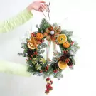 Christmas wreath with dried oranges, pine cones, cinnamon sticks, and a festive bow.