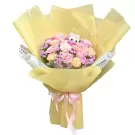 Bouquet of pink and peach roses with purple filler flowers, wrapped in yellow paper and tied with a pink ribbon.