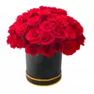 Round box of red roses with yellow trim.
