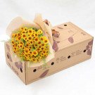 Bouquet of sunflowers wrapped in paper on a cardboard box with floral designs.