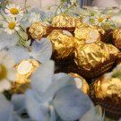 Ferrero Rocher chocolates mixed with blue hydrangeas and daisies.