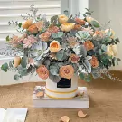 Elegant floral box with peach and pink roses, succulents, and greenery.