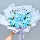 Blue and white roses in a bouquet with a "Happy Day" card.