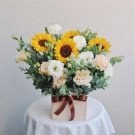 Wooden box with sunflowers, lisianthus, and other greenery, tied with a brown ribbon.