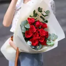 Red roses and eucalyptus bouquet with light tan paper wrapping.