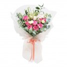 Pink and white roses bouquet with greenery, wrapped in sheer paper and tied with a coral ribbon.