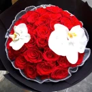 A bouquet of vibrant red roses with two delicate white orchids.