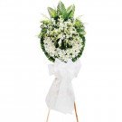 White orchid funeral wreath on a wooden stand with a white ribbon.