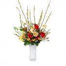 Vạn Lộc Tết flower arrangement with red roses, gerbera daisies, and pussy willow branches in a vase.
