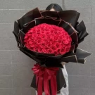 Large bouquet of 150 red roses in black and gold wrapping with a red ribbon.