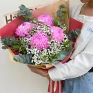 Pink peonies and baby's breath in a bouquet with eucalyptus leaves.