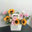 Floral arrangement in a white box with sunflowers, pink gerbera daisies, and white roses.