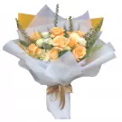 Bouquet of peach roses, white chrysanthemums, and greenery, wrapped in white paper with a gold ribbon.