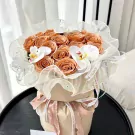 Peach roses and white orchids in a flowing sheer fabric wrap, tied with ribbon.
