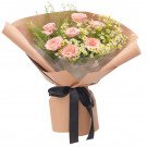 Pink cappuccino roses with daisies, wrapped in kraft paper and tied with a black ribbon.