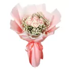 A bouquet of light pink roses and baby's breath, wrapped in pink paper and tied with a ribbon.