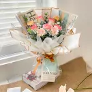 Bouquet of pink roses, gerbera daisies, and baby's breath wrapped in newspaper.