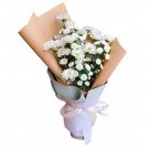 White chrysanthemums and Calimero flowers in a bouquet wrapped in brown and white paper with a pink ribbon.