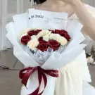 Red scarlet bouquet with white accents, wrapped in white paper and tied with a red ribbon.