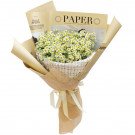 Bouquet of small white daisies with yellow centers, wrapped in beige paper and white tweed fabric.