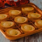 Golden bar-shaped pineapple cakes with soft crust and smooth filling in a gold tray.