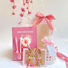 Pink gift set with notebook, pens, scented candle, and Women's Day card.