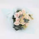 Bouquet of pale pink roses, daisies, and eucalyptus leaves wrapped in light blue paper.