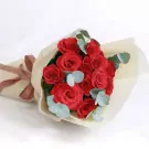 Bouquet of 12 red roses with eucalyptus leaves, wrapped in cream paper and tied with a brown ribbon.
