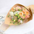 A bouquet of pink and peach roses, white lisianthus, and greenery wrapped in brown paper.
