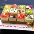 Nine Christmas mousse desserts in clear cups with fruit and snowflake decorations, on a platter with "All I want for Christmas is You!" written.