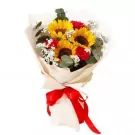 Bouquet of sunflowers and red roses with white filler flowers, wrapped in cream paper and tied with a red ribbon.