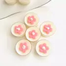 Six tea lights with pink flower decorations on a white background, with a silver wire in the upper left.