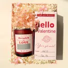 Valentine gift set with red candle, pink flowers, and "Hello Valentine" card.